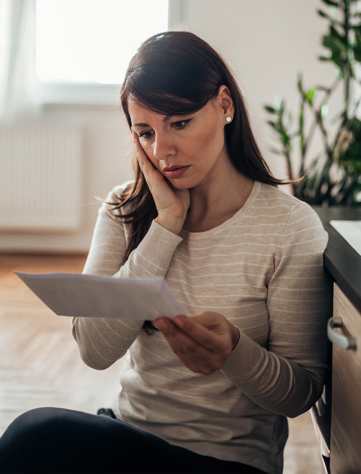 Stressed woman reading a letter at home 1