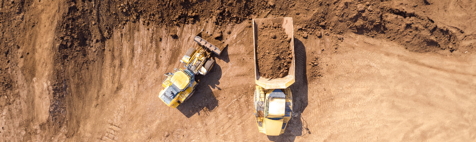 excavator loading soil onto an articulated hauler