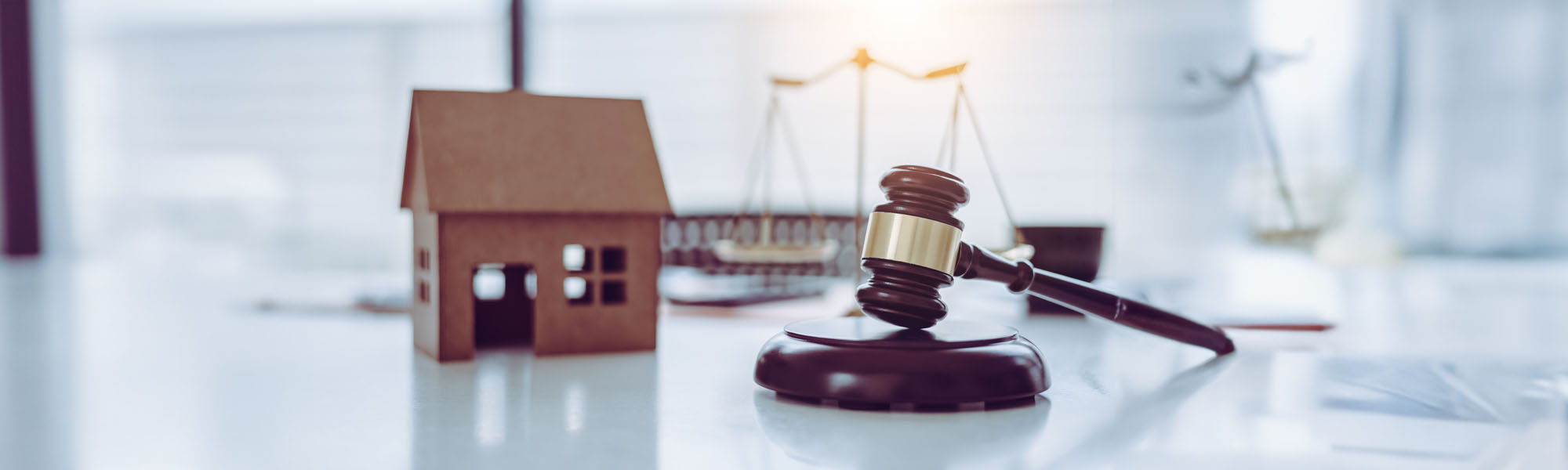 A judges gavel and sounding block besides a small wooden model of a house; Ramapo real estate law firm concept image