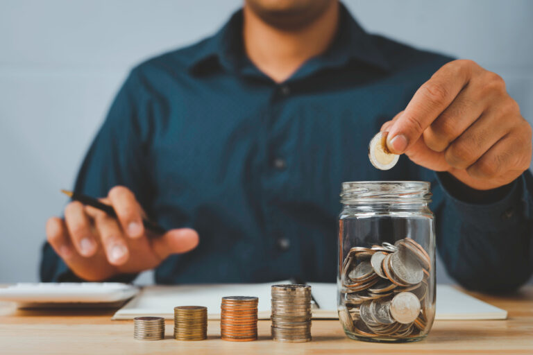 A businessman with a coin in a glass Along with pressing the calculator and write down savings for the future after retirement, ideas for saving money for the future and life after retirement