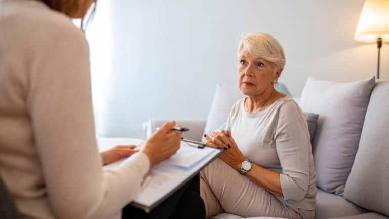 Geriatric psychology, mental therapy and old age concept - Sad unhappy senior woman patient and psychologist with clipboard taking notes at psychotherapy session.