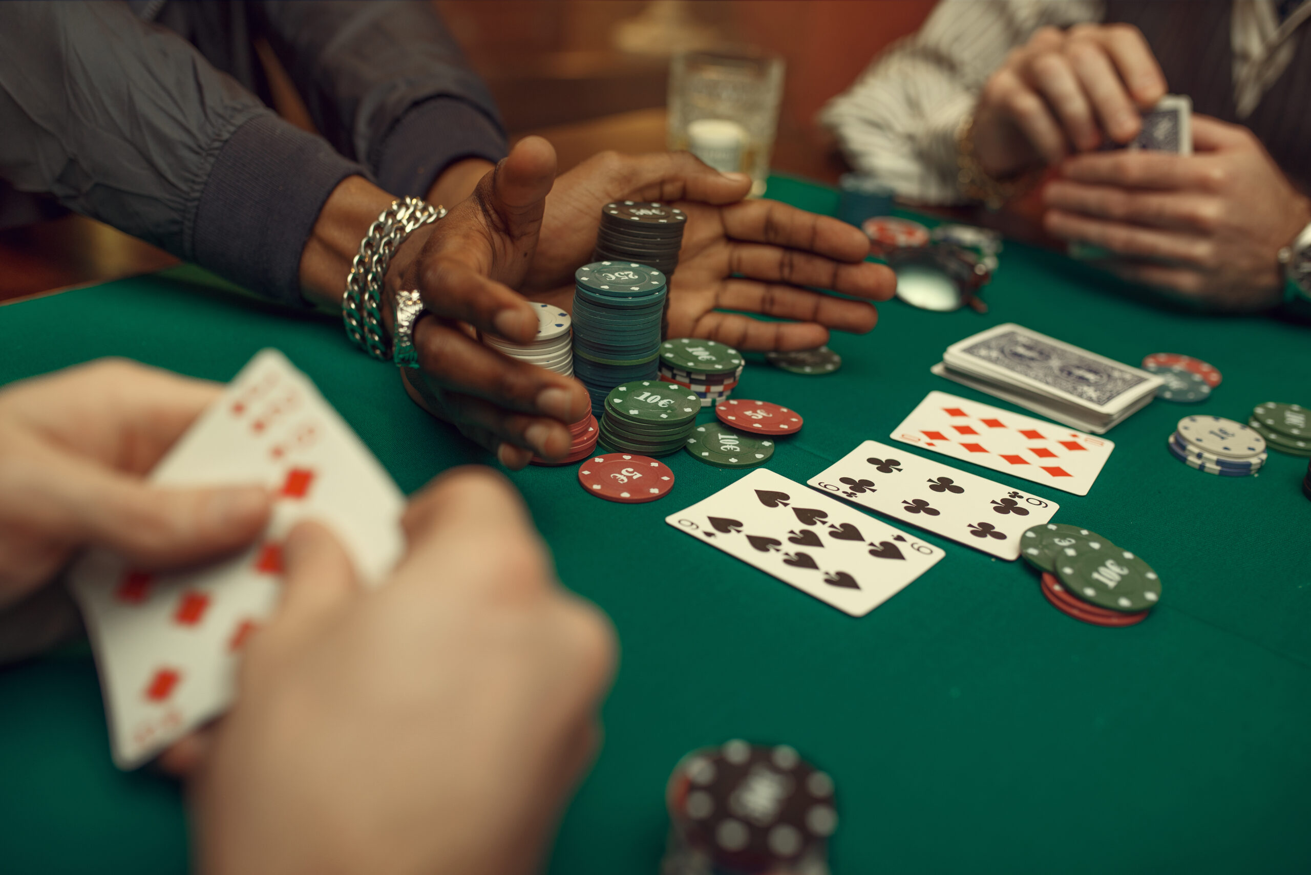 Poker players hands, gaming table on background