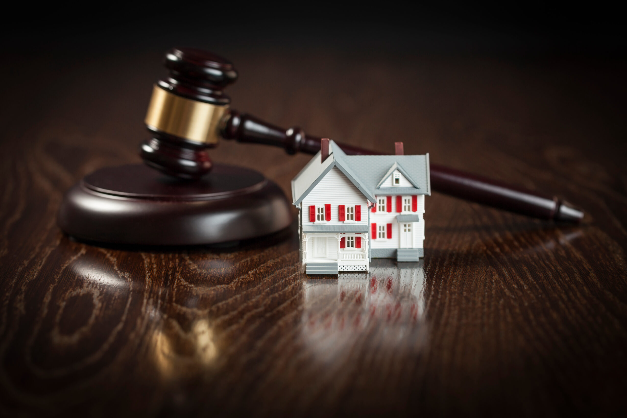 Gavel and Small Model House on Wooden Table.